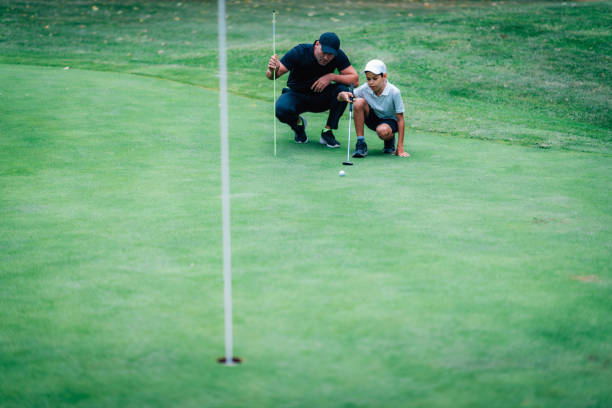 trening putting golfa. instruktor golfa z młodym chłopcem ćwiczącym na putting green - golf green practicing sports training zdjęcia i obrazy z banku zdjęć