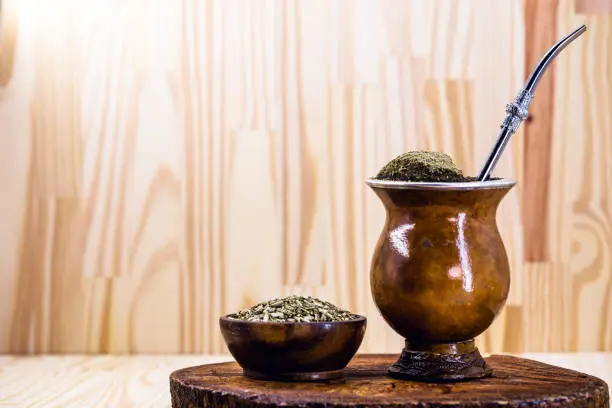 Photo of Chimarrão, or mate, is a characteristic drink of the culture of southern South America. mate bowl with mate herb, pump and accessories for preparing mate herb. Space for text.