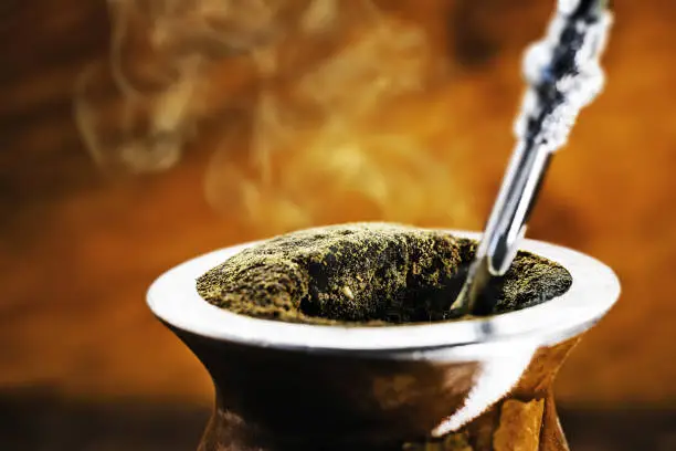 Photo of Yerba mate tea in calabash on wooden table. Traditional Argentine, Uruguayan and Brazilian drink. typical drink from rio grande do sul