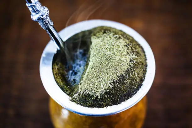 Photo of Yerba mate tea in calabash on wooden table. Traditional Argentine, Uruguayan and Brazilian drink. typical drink from rio grande do sul