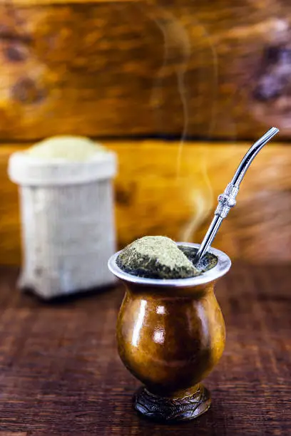 Photo of Yerba mate tea in calabash on wooden table. Traditional Argentine, Uruguayan and Brazilian drink. typical drink from rio grande do sul