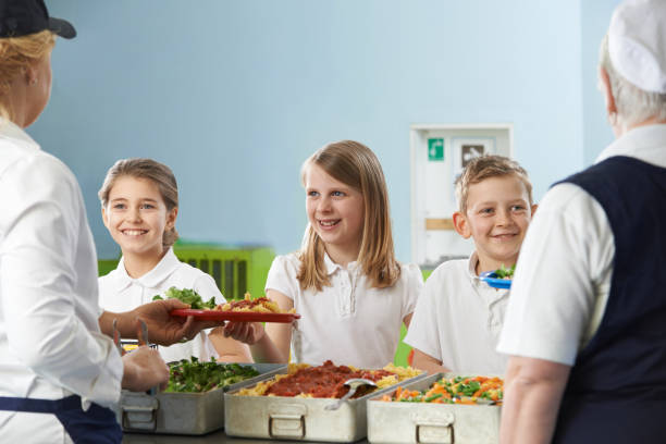 istock Pupils In School Cafeteria Being Served Lunch By Dinner Ladies 1217825128
