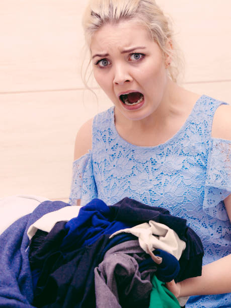 istock Unhappy girl sorting dirty clothes laundry. 1217825320