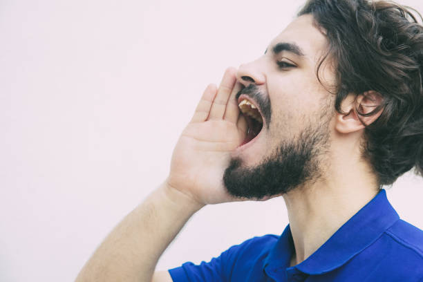 istock Side of excited guy shouting loud with hand at open mouth 1217827261