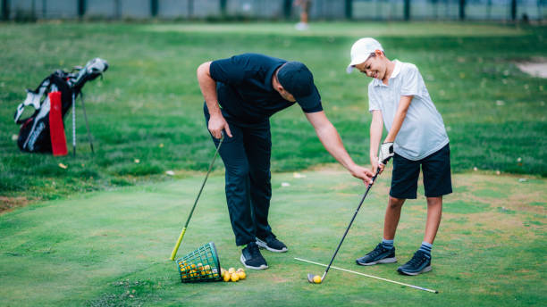 golfe – treinamento pessoal. instrutor de golfe ensinando o garoto a jogar golfe. - golf green practicing sports training - fotografias e filmes do acervo