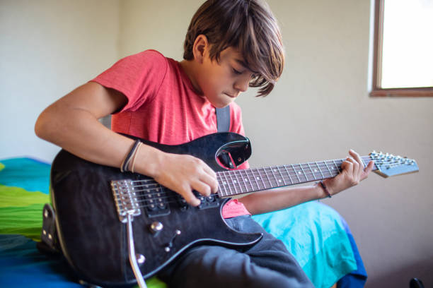 enfant préadolescent de latinx apprenant à jouer de la guitare électrique à la maison - guitar child music learning photos et images de collection