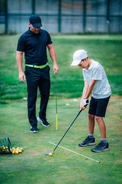 golfe – treinamento pessoal. instrutor de golfe ensinando o garoto a jogar golfe. - golf green practicing sports training - fotografias e filmes do acervo