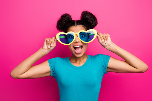 Photo of funky dark skin lady two buns chilling cool students party, summer time good mood wear heart shape sun specs blue casual t-shirt isolated magenta color background