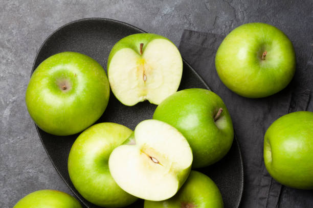 fruits verts mûrs de pomme sur la table foncée de pierre - granny smith apple photos et images de collection