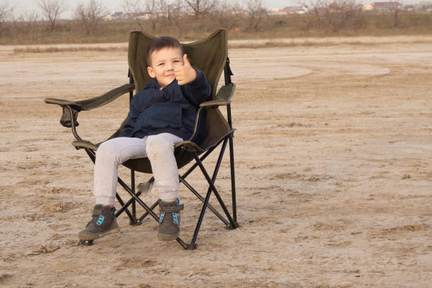 istock A 4-year-old boy sits on a folding chair on an empty beach during quarantine. 1217831067