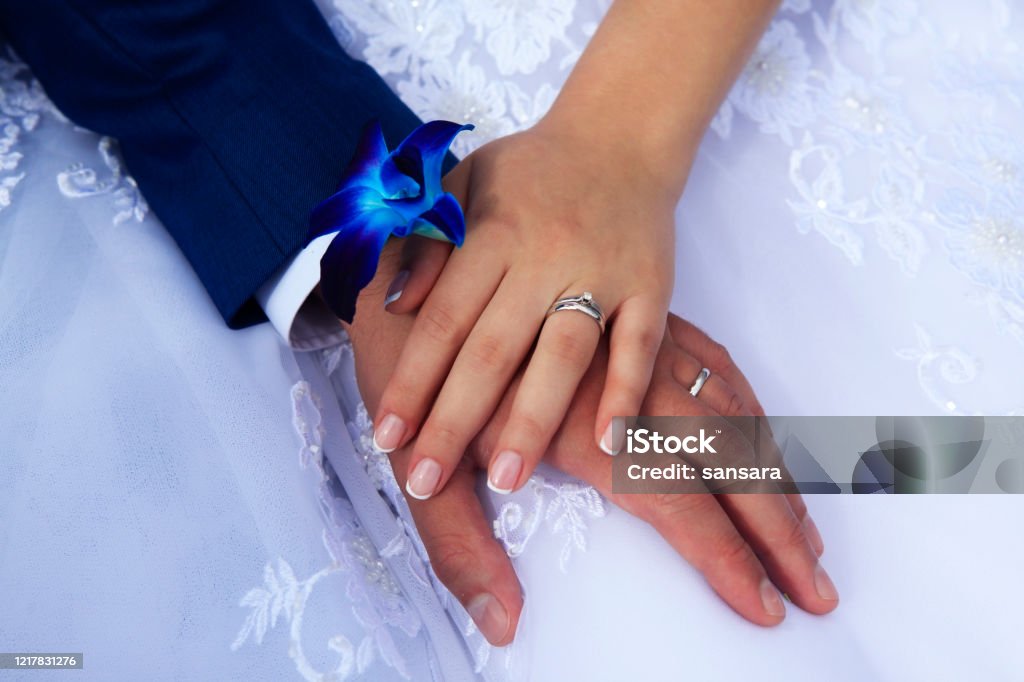 Hands of the bride and groom on the background of a wedding dress. Bride Stock Photo