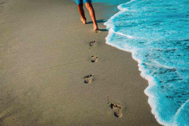 istock kid walking on beach leaving footprint in sand 1217834495