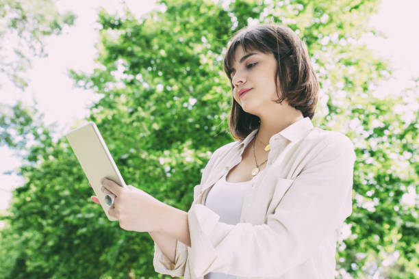 istock Smiling woman using tablet pc outdoors 1217836791