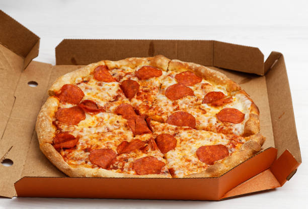 istock Closeup open box with pepperoni pizza on white wooden table. 1217838268