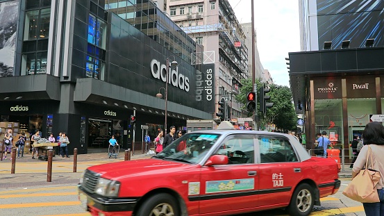 Hong Kong, China - December 5, 2016: red taxi cars in Peking road crossroad, with Adidas store on background.