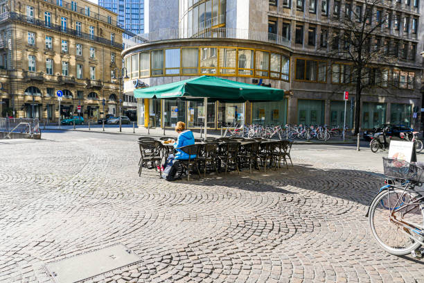 Coronavirus lockdown. Frankfurt, Germany. April 5, 2020. Single customer sitting at coffee shop table outdoors during covid-19 crisis.