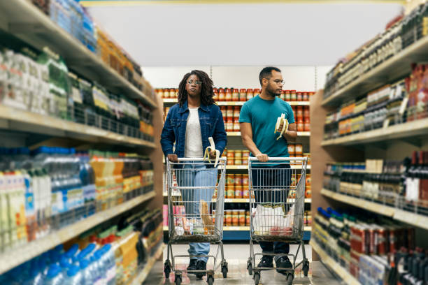 istock Focused young couple walking in aisle with alcohol drinks 1217847126