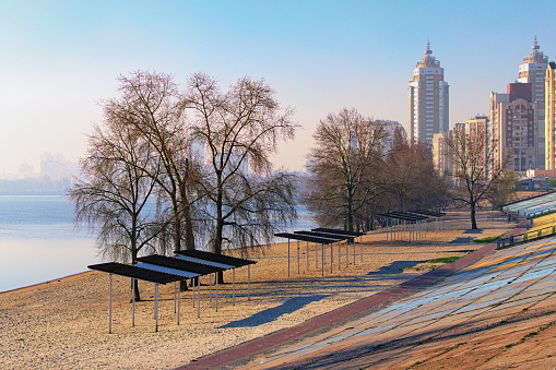 Picturesque spring morning landscape view of Dnieper River with the beach in modern Obolon district. Beautiful cityscape in morning smog in the background. Kyiv, Ukraine