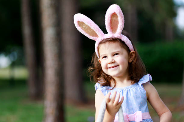 istock Little toddler girl with bunny ears. Easter eggs hunt 1217848598