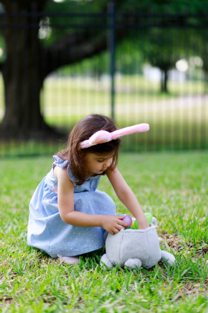 istock Little toddler girl with bunny ears. Easter eggs hunt 1217849590