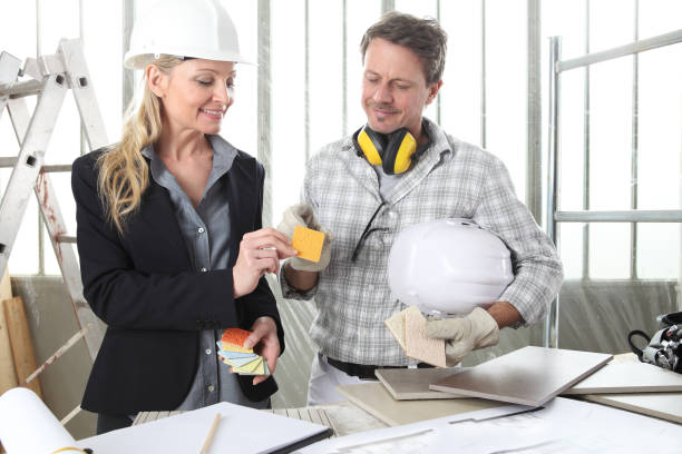 smiling man and woman architect interior designer and foreman worker together with color samples and decorative materials discussing the project for interior decoration in the inside the construction building site - home decorating interior designer blueprint planning imagens e fotografias de stock