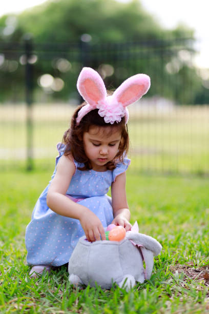 istock Little toddler girl with bunny ears. Easter eggs hunt 1217849857