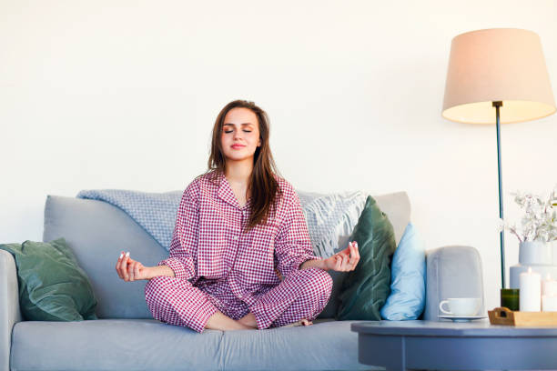 istock Optimistic lady with cup of hot beverage and candles sitting on the sofa 1217850197