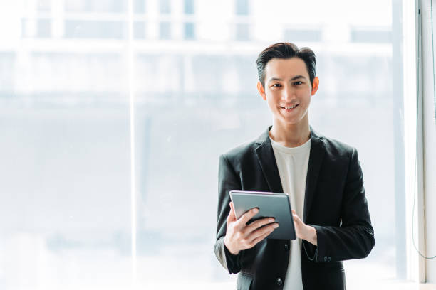 istock Asian chinese young smiling businessman using a digital tablet and look at camera in his office 1217851775