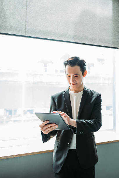 istock Asian chinese young businessman using a digital tablet with smiling face in his office 1217852599
