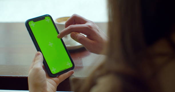 istock Businesswoman using mobile cell phone with green touch screen in cafe. GREEN SCREEN. Sharing messages on social media. 1217852688