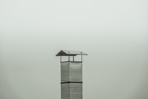 Old metal chimney on the roof on foggy day