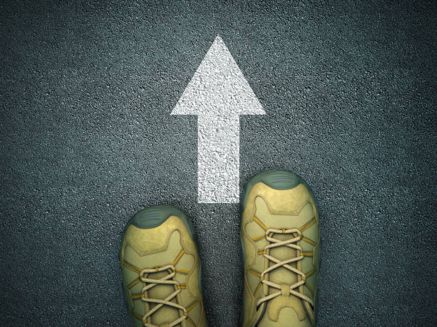 istock Feet on Asphalt Road with Arrow - 3D Rendering 1217855192