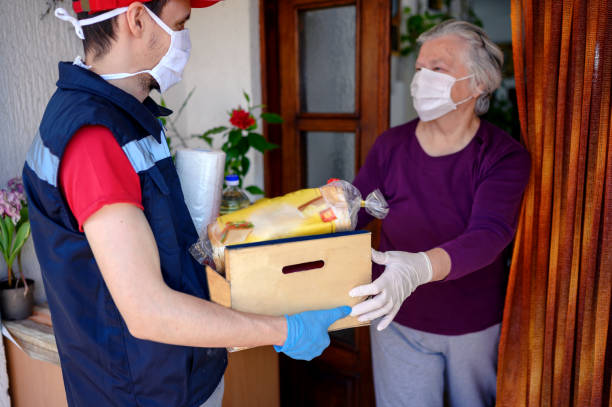 Food delivering at home address Delivering food ordered online while in home isolation during quarantine. Courier in protective mask delivers parcel to client. home delivery photos stock pictures, royalty-free photos & images
