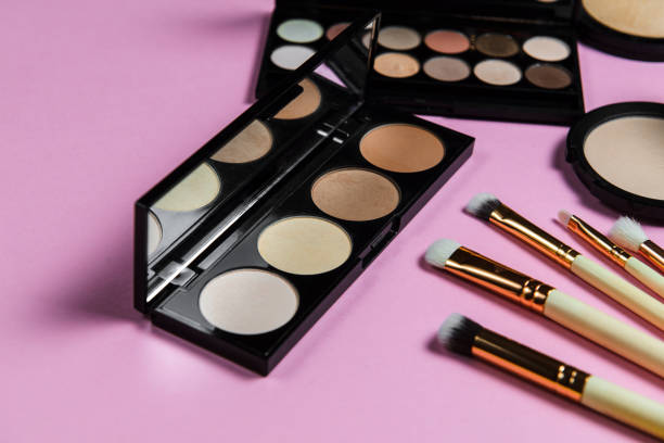 istock Makeup brushes, powder, eyeshadow palette, foundation for the face on a light pink background with place for text, side view 1217860090