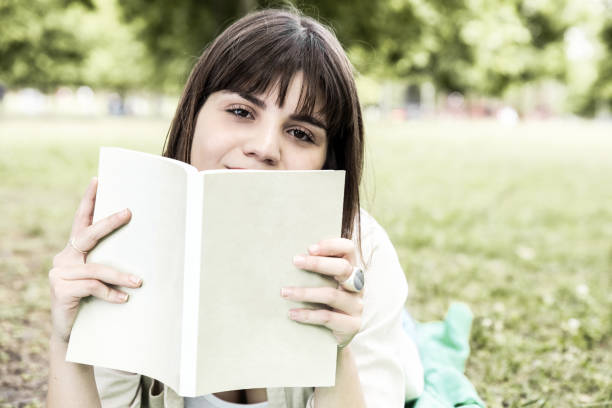 istock Young woman reading book in park 1217862848