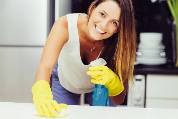 istock Positive young housewife using spray for cleaning 1217864470