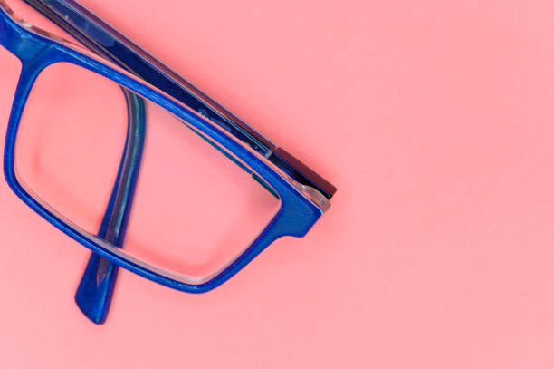 Close up of Blue eyeglasses on pink background, top view.