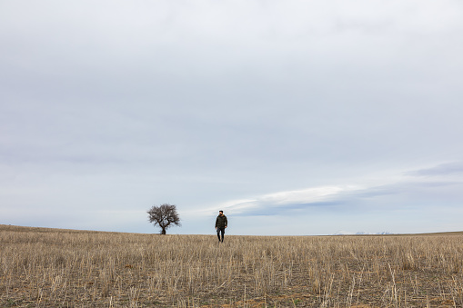 Single tree and lonely man in a field.