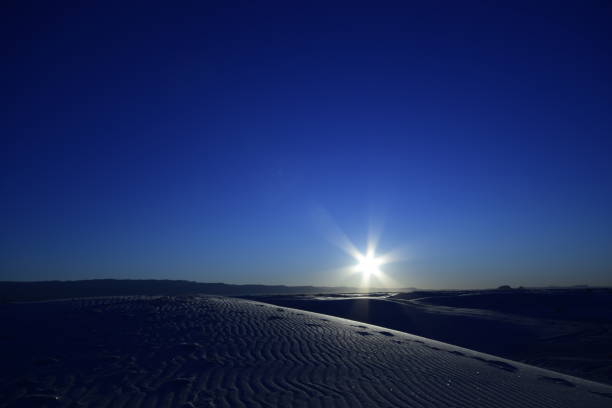 schöne sanddünen, die sich über den horizont erstrecken, während ein wunderschöner idyllischer sonnenaufgang mit sonnenstrahlen gegen klar blauen lebhaften himmel - new mexico landscape sky ethereal stock-fotos und bilder