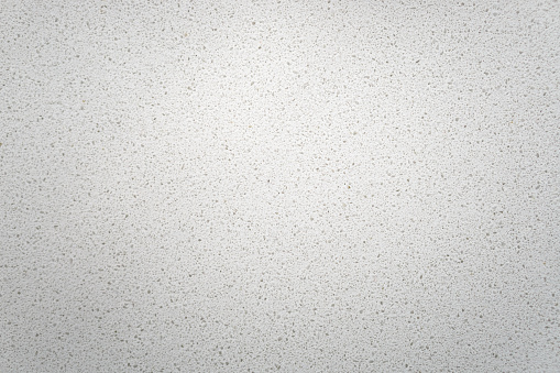 White quartz background countertop. This light background is taken from a bright off-white quartz kitchen counter. The subtle texture can be used as surface or table backdrop graphic design element.