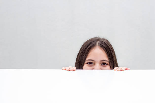 흰색 배경에 고립 된 테이블 아래에서 찾고있는 어린 소녀의 초상화 - child discovery surprise playing 뉴스 사진 이미지