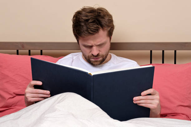 istock Reading an exciting book sitting on bed at home. 1217871692