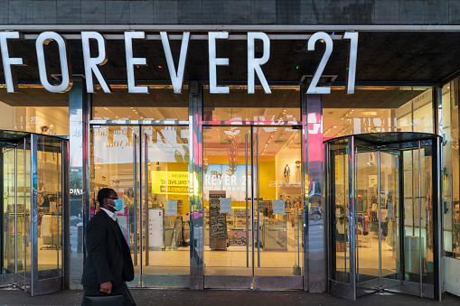 New York, NY, USA - April 6, 2020: Black man wearing a protective mask walking in front of closed FOREVER 21 department store in Times Square during the COVID-19 pandemic.