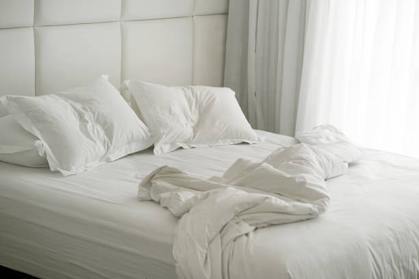 istock Hotel bed after use. Dirty bed pillow blanket room. 1217872416