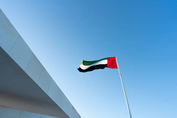 les drapeaux des émirats arabes unis agitant contre le beau ciel bleu - flag of the united arab emirates photos et images de collection