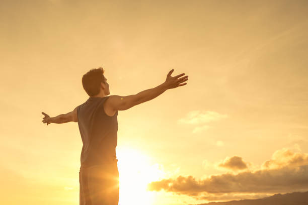 istock Young strong man with arms open wide facing the sunset. 1217874557