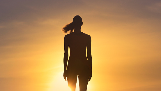 Woman standing watching sunset.