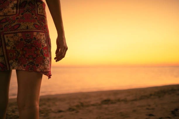 istock Woman standing on the beach watching sunset 1217875440