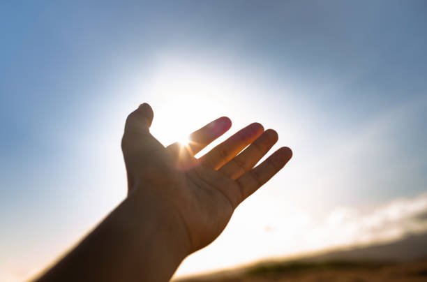 暖かい日差しに触れる朝の光に手を差し伸べている人。 - praying men god kneeling ストックフォトと画像