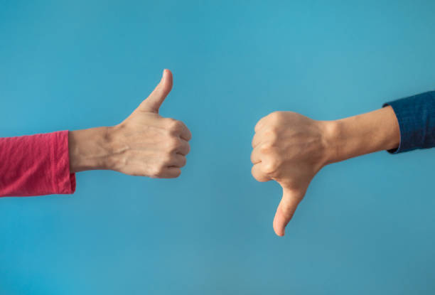 Two people making hand sign thumbs up and thumbs down, yes or no, like or dislike concept. Two people making hand sign thumbs up and thumbs down. pessimism photos stock pictures, royalty-free photos & images